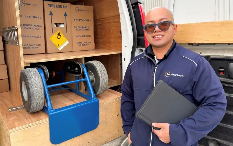 A Careica Health Home Oxygen Technician stands in front of a van